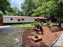 A single-story home featuring a red roof, manicured lawn, garden beds, and a gravel driveway at 475 Dot Faris Rd, Catawba, SC 29704