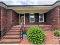 Inviting front porch with brick steps, black railing, and manicured greenery at 6339 River Front Dr, Harrisburg, NC 28075