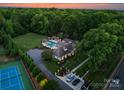 Majestic estate with manicured lawns, a sparkling pool, tennis court, and a grand driveway leading to the home at 8300 Fairview Rd, Charlotte, NC 28226