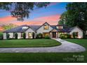 Elegant home with a well-manicured lawn and a circular driveway showcasing its classic architectural design at 8300 Fairview Rd, Charlotte, NC 28226