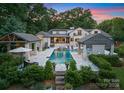 Stunning pool area surrounded by luxurious cabanas, lush landscaping, and a beautifully designed home at twilight at 8300 Fairview Rd, Charlotte, NC 28226