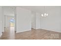 Open-concept living space with hardwood floors, white walls, modern chandelier and view to the neighborhood at 9528 Maltese Dr, Gastonia, NC 28056