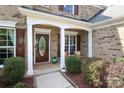 Cozy front porch featuring a stylish front door, seating, and professionally landscaped flowerbeds at 10217 Falling Leaf Dr, Concord, NC 28027
