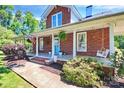Inviting brick front porch with white columns, swing, and a charming blue front door at 1105 S Point Rd, Belmont, NC 28012