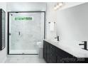 Elegant bathroom with a glass-enclosed shower, marble walls, and dual vanities with modern fixtures at 12305 Gambrell Dr, Charlotte, NC 28278