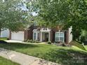 Well-maintained two-story brick home with manicured lawn and mature trees shading the front yard at 13123 Ashley Meadow Dr, Charlotte, NC 28213