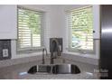 Close-up of kitchen sink area featuring stainless steel sink, brass faucet, and window with blinds at 14621 Waterside Dr, Charlotte, NC 28278