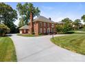 Well-manicured grounds surround this attractive brick home with a circular driveway and attached garage at 208 Huntley Pl, Charlotte, NC 28207