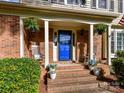 Inviting front porch featuring a bright blue door, rocking chairs, hanging plants, and brick steps at 2315 Lawton Bluff Rd, Charlotte, NC 28226