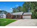 Classic brick home featuring a covered front porch, attached two car garage, and a spacious driveway at 2502 Gold Rush Dr, Lincolnton, NC 28092