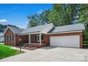 Traditional brick home showcasing a covered porch with a swing and an attached two car garage at 2502 Gold Rush Dr, Lincolnton, NC 28092