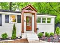 Close up of front door with wood accents, white painted brick, manicured yard and trimmed shrubs at 3120 Parkway Ave, Charlotte, NC 28208