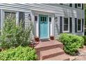 Inviting front entryway features a bright blue door, brick steps, and well-maintained landscaping with black shutters at 417 Florence Cir, Statesville, NC 28625