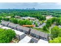 Daytime aerial view of gray townhomes with the Charlotte skyline in the background with lush, green trees at 556 Billingsley Rd, Charlotte, NC 28211