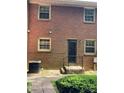 Brick townhouse back view features windows, door to a small deck with black railing and stone walkway at 623 S New Hope Rd # 9, Gastonia, NC 28054