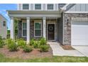 Inviting front porch with stone accents, decorative columns, and a charming front door with a wreath, enhancing curb appeal at 699 Kitfox Nw Dr, Concord, NC 28027