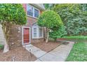 Close-up of home's entrance highlighting the red door, brickwork, and tidy landscaping at 8221 Pineville Matthews Rd # G, Charlotte, NC 28226