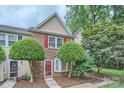Inviting townhouse featuring brick facade, red shutters, and lush front yard landscaping at 8221 Pineville Matthews Rd # G, Charlotte, NC 28226
