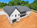 Aerial view showcasing a new home with a dark roof, garage, and a serene wooded backdrop at 124 Starboard Ln, Statesville, NC 28677