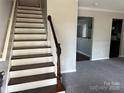 An entryway view of a staircase and carpeted living room in a modern home at 1300 Braveheart Ln, Charlotte, NC 28216