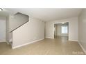 A spacious living room, featuring neutral walls, tiled floors, and an open staircase, transitions into another room at 1905 Mereview Ct # 21, Charlotte, NC 28210