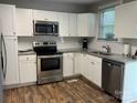 Bright kitchen featuring stainless steel appliances, granite countertops, and wood flooring at 247 E Cabarrus Ave, Concord, NC 28025