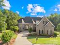 Elegant brick home featuring arched windows, a stately roofline, and professional landscaping under a brilliant blue sky at 458 Inverness Pl, Rock Hill, SC 29730