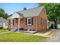 A charming brick house has black shutters, a red door, and an attached covered area at 604 Meadowbrook Rd, Kings Mountain, NC 28086