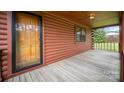 Rustic log cabin home featuring a covered front porch with wood flooring and exposed log walls at 8464 Robinson Church Rd, Charlotte, NC 28215