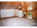 Spacious living room with wood paneling, adjoining kitchen and access to outdoor deck at 8464 Robinson Church Rd, Charlotte, NC 28215