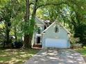 Charming two-story home with a light green exterior, arched windows and a two-car garage surrounded by mature trees at 9907 Furlong Trl, Charlotte, NC 28269