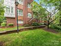 Attractive brick condo building with stairs leading to upper-level units, nestled amongst lush greenery at 100 N Laurel Ave # 107, Charlotte, NC 28207
