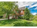 Two-story brick home showcasing a well-manicured lawn, mature trees, and blue shutters at 10418 Goosefoot Nw Ct, Concord, NC 28027