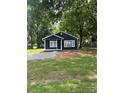 Quaint blue home surrounded by mature trees, featuring a well-maintained lawn at 2123 W Sixth Ave, Gastonia, NC 28052