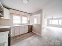 Modern kitchen with stainless steel appliances, white cabinets, and light wood-look flooring opens to the living room at 2123 W Sixth Ave, Gastonia, NC 28052