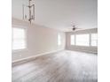 Bright and airy living room with large windows, light gray walls, modern chandelier, and light wood-look flooring at 2123 W Sixth Ave, Gastonia, NC 28052