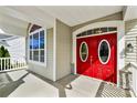 Close-up of a striking red front door with oval windows, set in a bright, welcoming entryway at 2830 Berkhamstead Cir, Concord, NC 28027