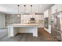 Bright kitchen featuring a large island, stone accent wall, stainless steel appliances, and modern cabinetry at 300 Hidden Cove Ln, Matthews, NC 28104