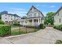 Attractive two-story home with a charming front porch, enhanced by a black wrought iron fence at 423 State St, Charlotte, NC 28208
