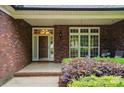 Charming front porch with brick accents, a wooden door, and lush landscaping offering a welcoming entrance at 4860 Sherborne Dr, Harrisburg, NC 28075