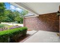 Spacious front porch featuring brick accents, a covered ceiling, and lovely landscaping for added curb appeal at 4860 Sherborne Dr, Harrisburg, NC 28075
