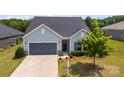 Charming single-story home with a well-manicured lawn, a gray garage door, and light blue siding at 5727 Lavaux Ct, Charlotte, NC 28214