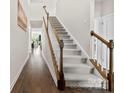 Hallway view featuring a carpeted staircase with wood railings and dark wood floors leading into the house at 5727 Lavaux Ct, Charlotte, NC 28214