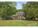 Beautiful brick home with a well-manicured lawn and mature trees, offering a picturesque curb appeal at 6040 Morris Farm Ln, Mint Hill, NC 28227