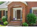 Charming front entrance featuring a classic wood door, brick steps, and manicured landscaping at 7103 Forest Ridge Rd, Matthews, NC 28104
