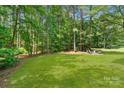 Serene backyard with lush green grass, mature trees, and an outdoor sitting area perfect for relaxation at 104 Whiterock Dr, Mount Holly, NC 28120