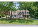 Beautiful two-story home surrounded by mature trees, featuring a stone facade, shutters, and a well-kept lawn at 105 Chippewa Trl, China Grove, NC 28023