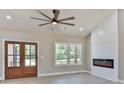 Well-lit living room features a large ceiling fan, fireplace, and views of the outdoors at 115 Falling Creek Dr, Statesville, NC 28625