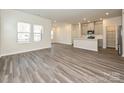 Bright, open-concept living space with modern gray wood flooring, large windows, and adjacent kitchen at 1223 Morehead Dr, Salisbury, NC 28144