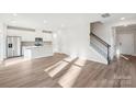 Bright open-concept living area with light wood floors adjacent to a modern kitchen and staircase at 125 Canoga Ave, York, SC 29745